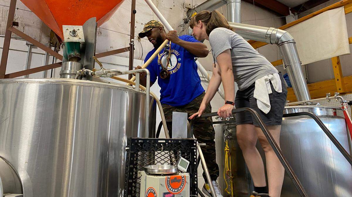Fish Scales of Nappy Roots stirs the mash of Backroads Blackberry Berliner with Country Boy Brewer, Stephanie Miracle.