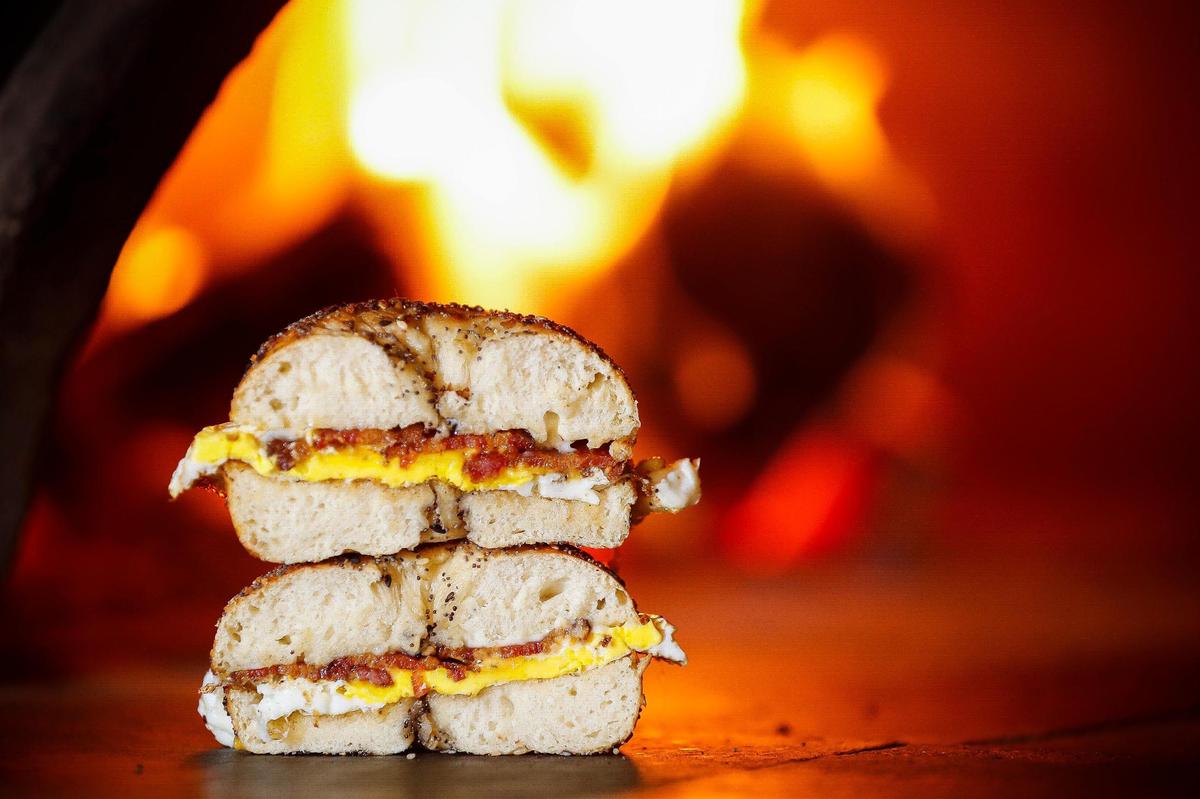 The bacon egg and cheese bagel made with Broadbent bacon, a local fried egg, garlic mayo and cheese, sits near the wood fired oven at Pearl’s in Lexington. Bagels at Pearl’s are hand rolled before being placed on cedar planks and roasted in the wood-fired oven.