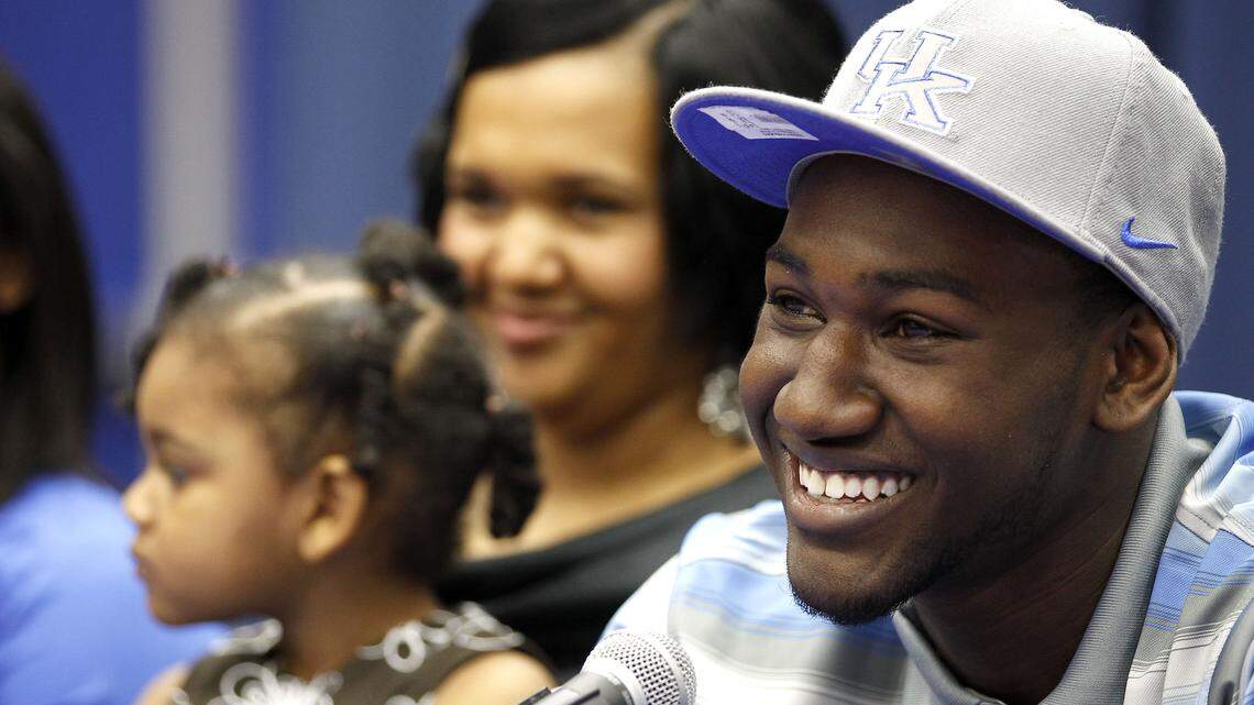 Dominique Hawkins, with mom Denise Hawkins holding his 3-year-old sister Sania Anderson on the left, smiled after making the announcement that he has committed to play basketball at the University of Kentucky, during a morning assembly in the gym at Madison Central High School in Richmond Ky., Wednesday, April 10, 2013. The The 6-foot-1 combo guard, who led the Indians to their first Sweet Sixteen title last month, made the announcement in front a packed gym that included teammates, family, friends, and the student body. Photo by Charles Bertram | Staff