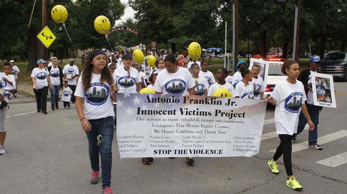 Danielle Puckett, 13, left, and Victoria Shy, 18, carry the banner as they lead the We Care Peace Walk departing Duncan Park in Lexington, Ky., Saturday evening, July 19, 2014. Photo by Matt Goins