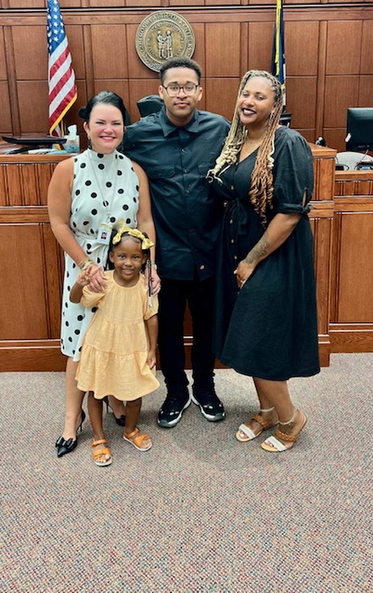 District Judge Lindsay Hughes Thurston (left) poses with a JTC graduate, his sister, and mom, Ashley West (right).