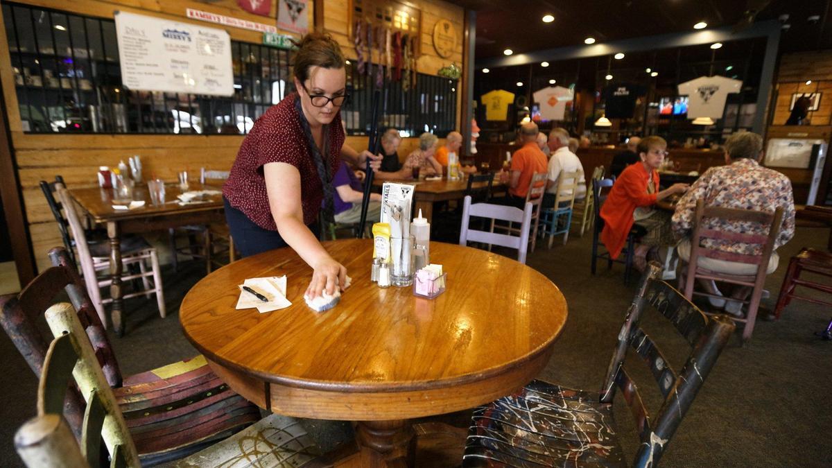 Ramsey’s Diner general manager Promise Griffith wipes off a table Wednesday for more guests to eat at the West Zandale Drive restaurant. Ramsey’s Diners across Lexington are facing a staffing shortage forcing waitresses to serve more tables than normal.