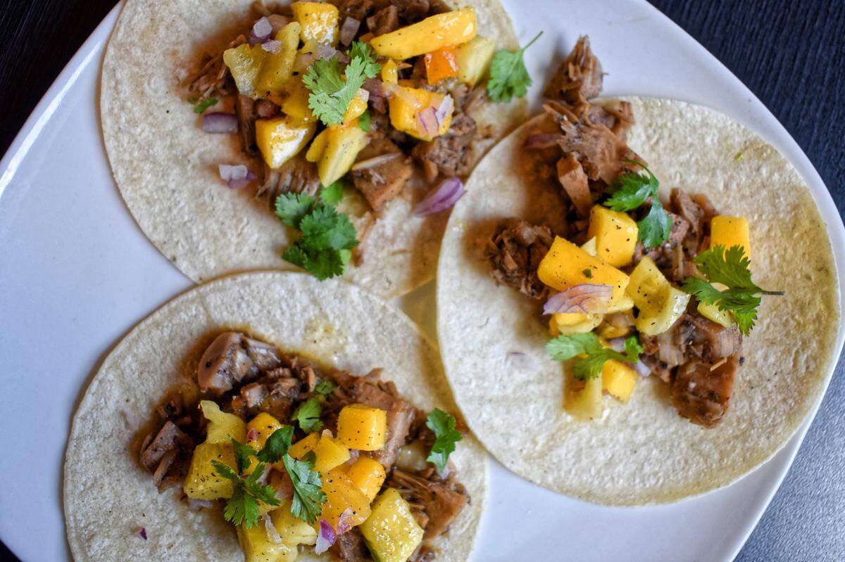 Jackfruit tacos, featuring a spicy stewed fruit with the taste and texture of meat, comes topped with mango-pineapple salsa.