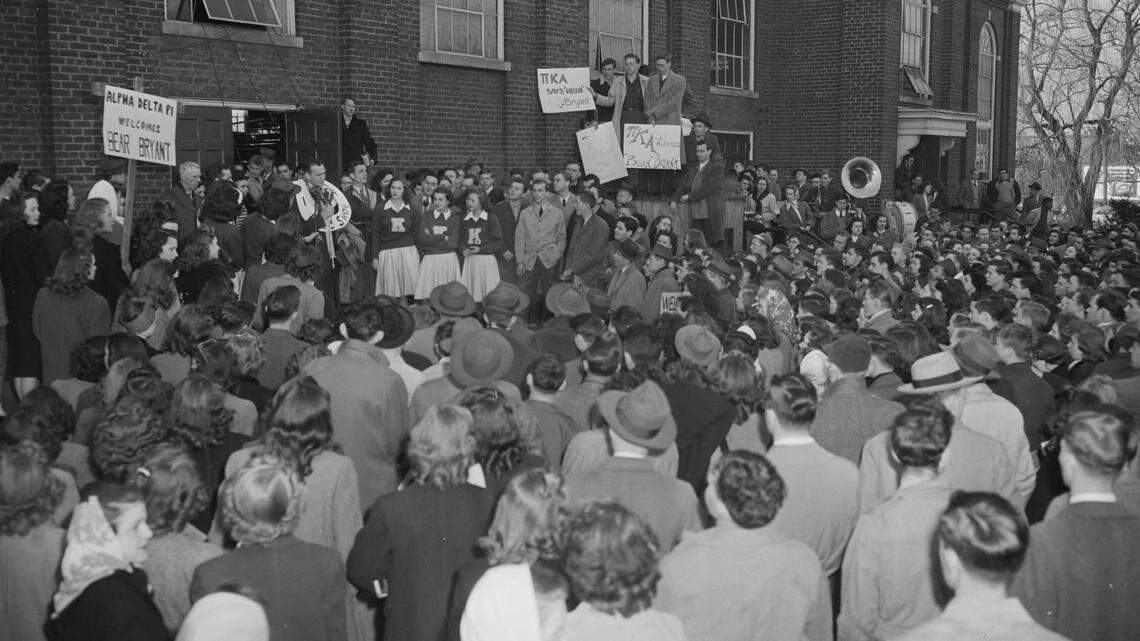 Paul "Bear" Bryant received a modest welcome outside Alumni  Gym when he was hired as the Kentucky football coach in 1946. Bryant wore a cardboard "hoss shoe" around his neck as he pledged to keep horse collars from following UK's name on scoreboards.           