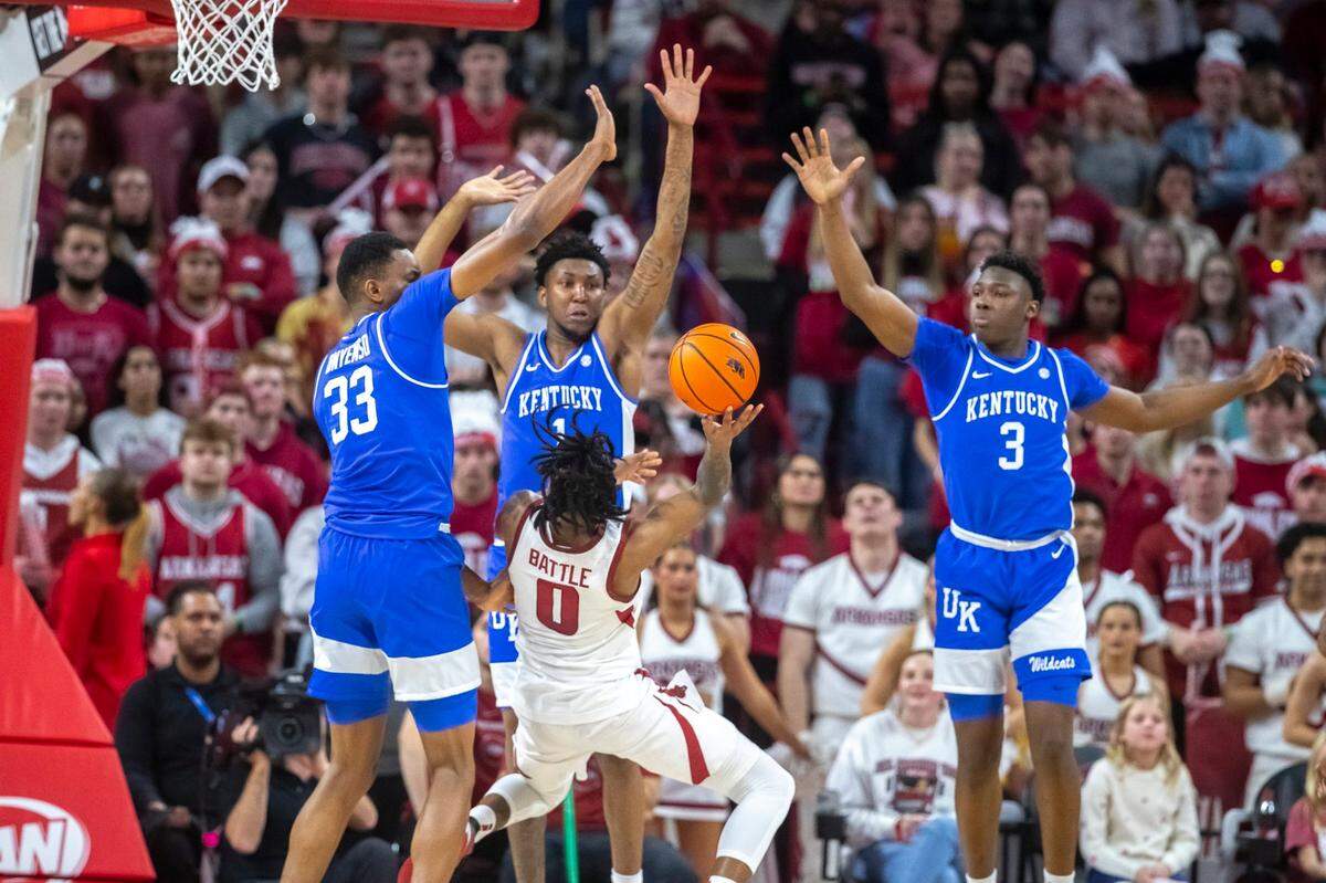 Kentucky’s Ugonna Onyenso (0), Justin Edwards (1) and Adou Thiero (3) enveloped Arkansas’ Khalif Battle on a drive to the basket during the Wildcats’ win in Fayetteville on Saturday. UK limited the Razorbacks to 33.3 percent shooting.