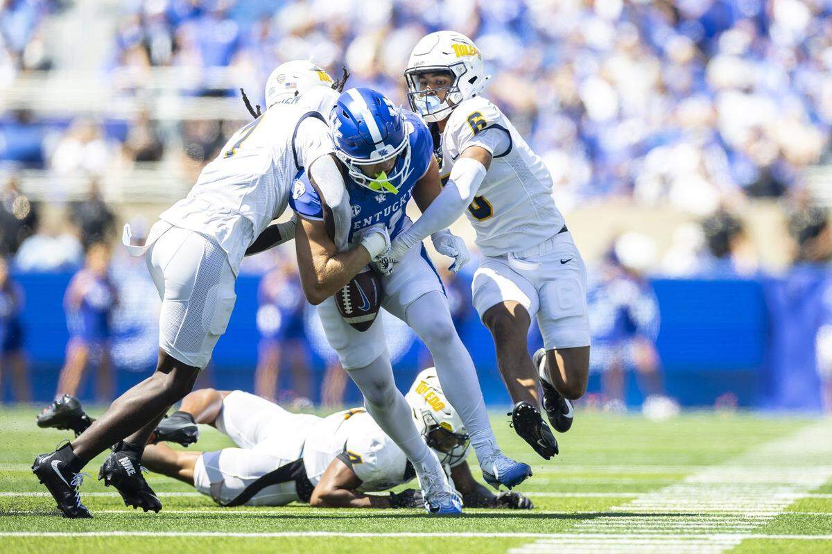 Toledo safeties Emmanuel McNeil-Warren (7) and Braden Awls (6) strip the ball from Kentucky tight end Willie Rodriguez (81) during Saturday’s game at Kroger Field.