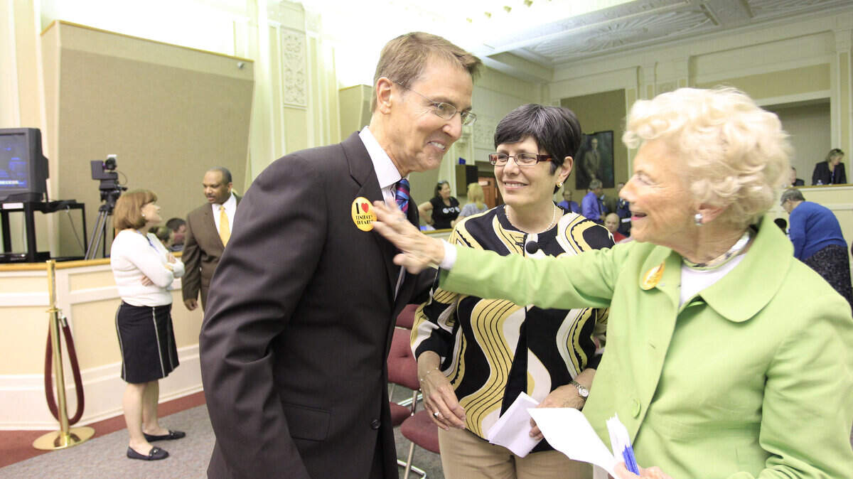 Vice Mayor Linda Gorton, center, watched as former Vice Mayor Isabel Yates put a Kentucky Theatre sticker on Mayor Jim Gray on Tuesday after he introduced his budget plan.