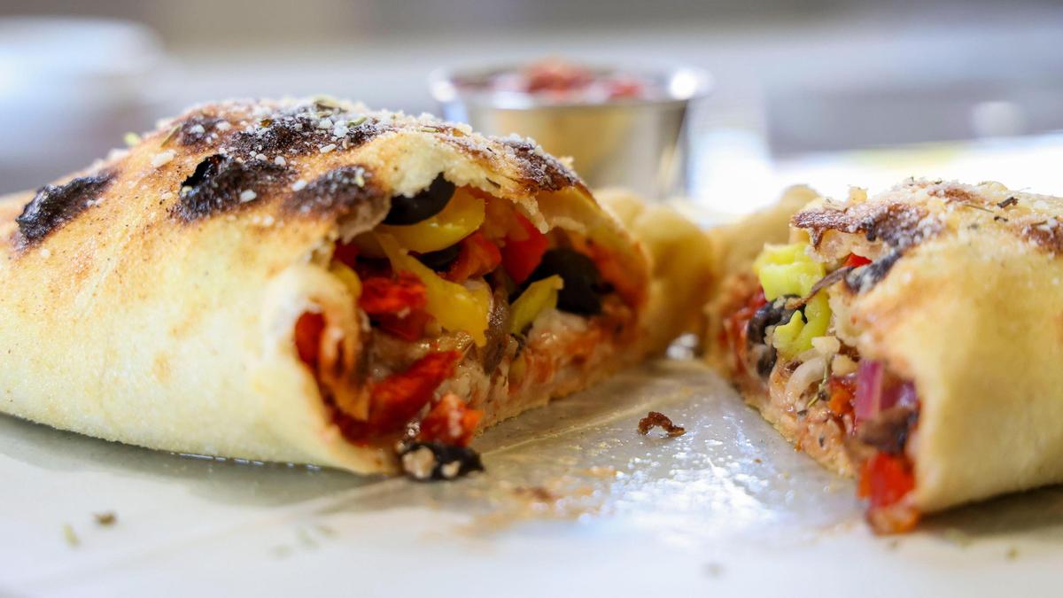 A Green Goddess calzone ($17) is stuffed with pesto sauce, mozzarella, crumbled feta, choice of meat, mushrooms, black olives, red onions and minced garlic. Calzone’s are served with homemade red sauce.