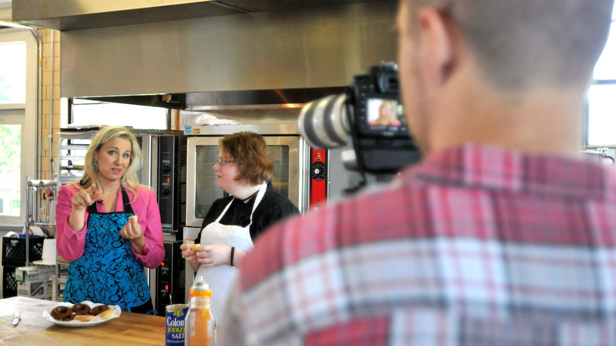 Amy Hess, left, host of Local Traveler, interviewed Midway School Bakery general manager Carrie Warmbier while Matt Webb taped them for an episode of the Gray TV show that airs on educational stations.