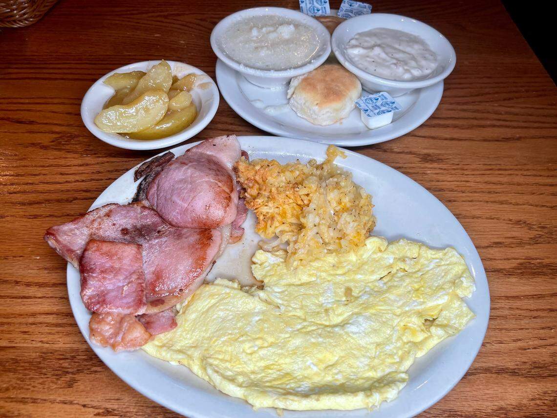 Cracker Barrel’s ‘Country Boy Breakfast.’ Three eggs, grits, fried apples, hashbrown casserole, and biscuits and gravy, shown with country ham.