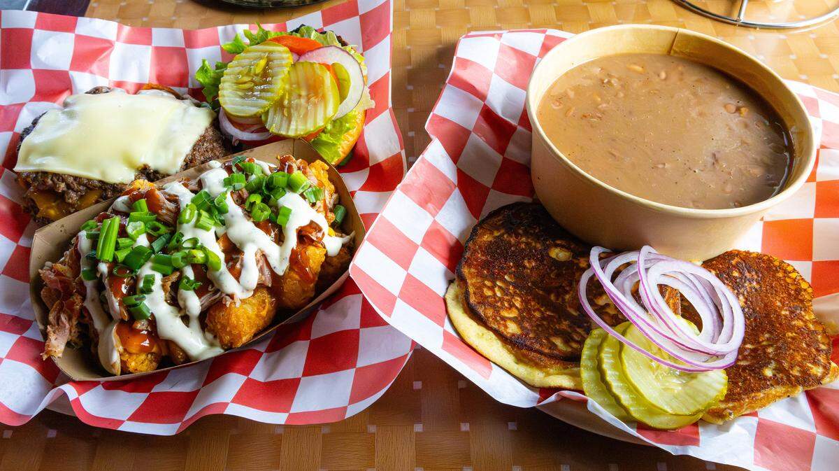 An OG Smash Burger with a side of Loaded BBQ Tot-Chos, and a bowl of Mamaw's Soup Beans with 2 pieces of sweet fried cornbread at the new barbecue restaurant, Nolo's On The Levee, on Jan. 23, 2026, in Mt. Sterling, Ky.