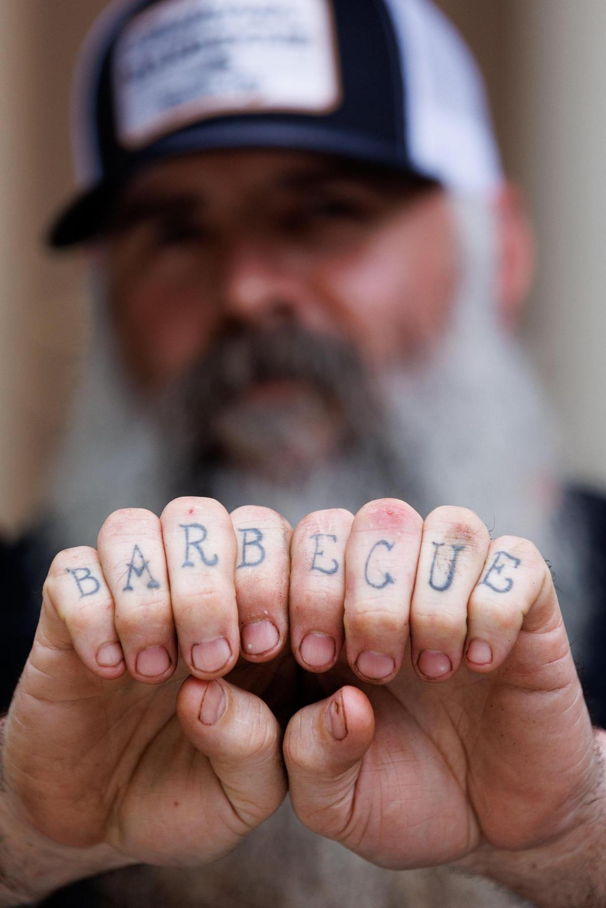 Shawn Thatcher shows off his barbecue tattoo on Sunday, June 12, 2022, at Thatcher Barbecue Company in Slade, Kentucky.