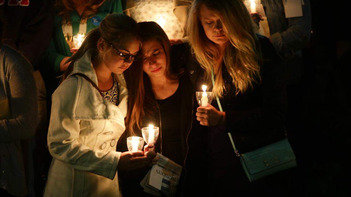 Rachel Wilson, left, Courtney Gaskill and Ashley Jones held one another during Monday night's memorial and candlelight vigil at UK.