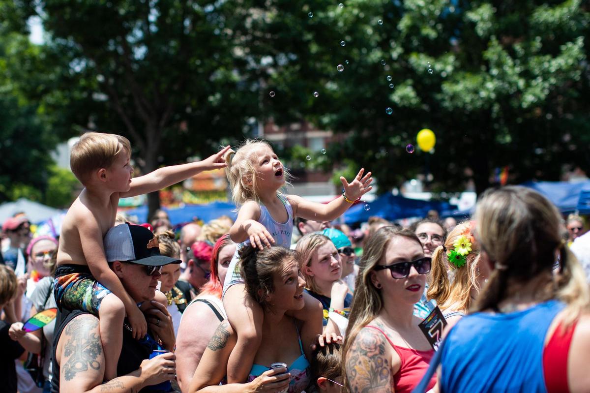 Phoenix and Damion Bennett reach to play with bubbles floating during a drag show at the annual Lexington Pride Festival in front of the Robert Stephens Courthouse in Lexington, Ky., Saturday, June 25, 2022.