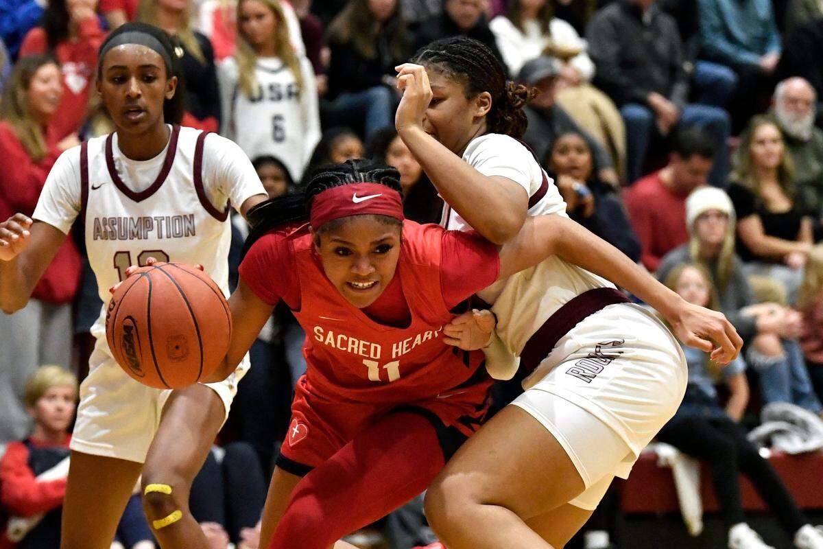 Sacred Heart's ZaKiyah Johnson (11) dribbles around the defense of Assumption's Kyleigh Hall (10) during the second half of their game, Sunday, Jan. 19 2025 in Louisville Ky. Sacred Heart won 73-42.
