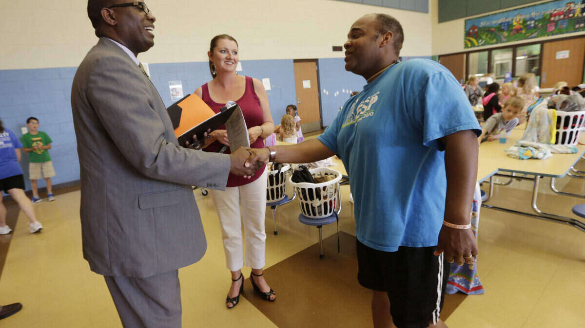 Candidate Emmanuel "Manny" Caulk  greeted Brian Hodge, who was helping with a summer camp at  Wellington Elementary School in Lexington, Ky., on June 23, 2015. Principal Julie Strange is in center. Caulk is currently the Superintendent of the Portland Public Schools in Maine. Photo by Pablo Alcala | Staff