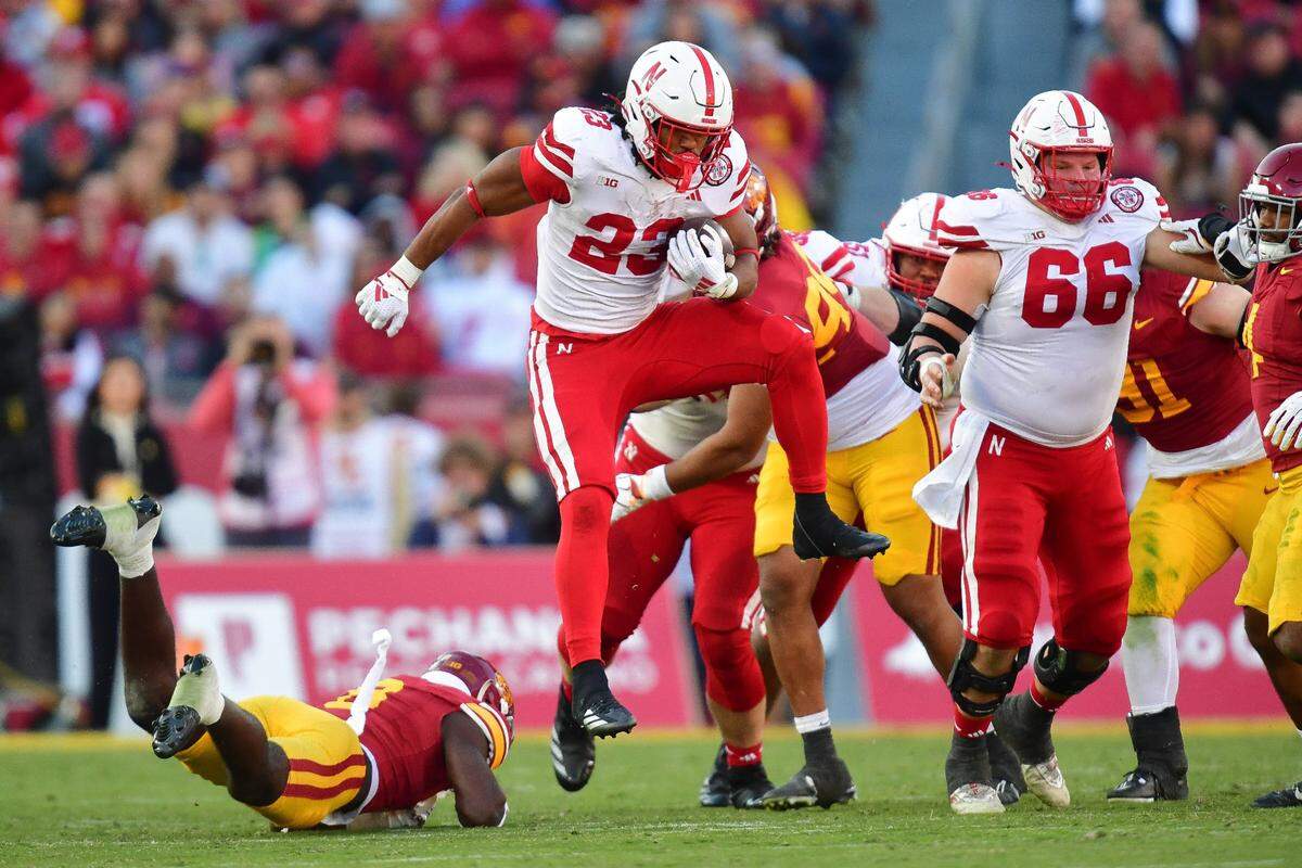 Nov 16, 2024; Los Angeles, California, USA; Nebraska Cornhuskers running back Dante Dowdell (23) jumps over Southern California Trojans safety Zion Branch (8) during the second half at the Los Angeles Memorial Coliseum. Mandatory Credit: Gary A. Vasquez-Imagn Images