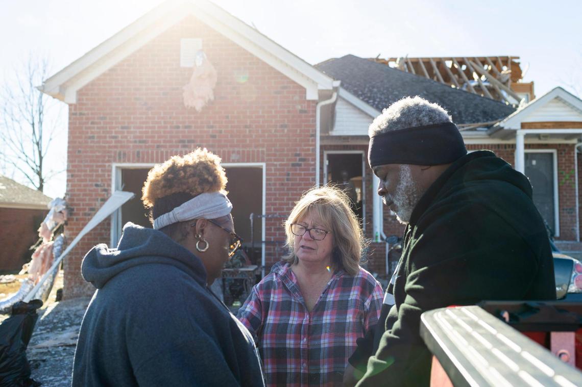Anthony Hickey Sr. prays with Laura Cardwell (center) and Brittani Kemp (left) while taking a break from cleaning out his apartment from debris after the tornado swept through Friday night in Bowling Green, Ky., Sunday, December 12, 2021.