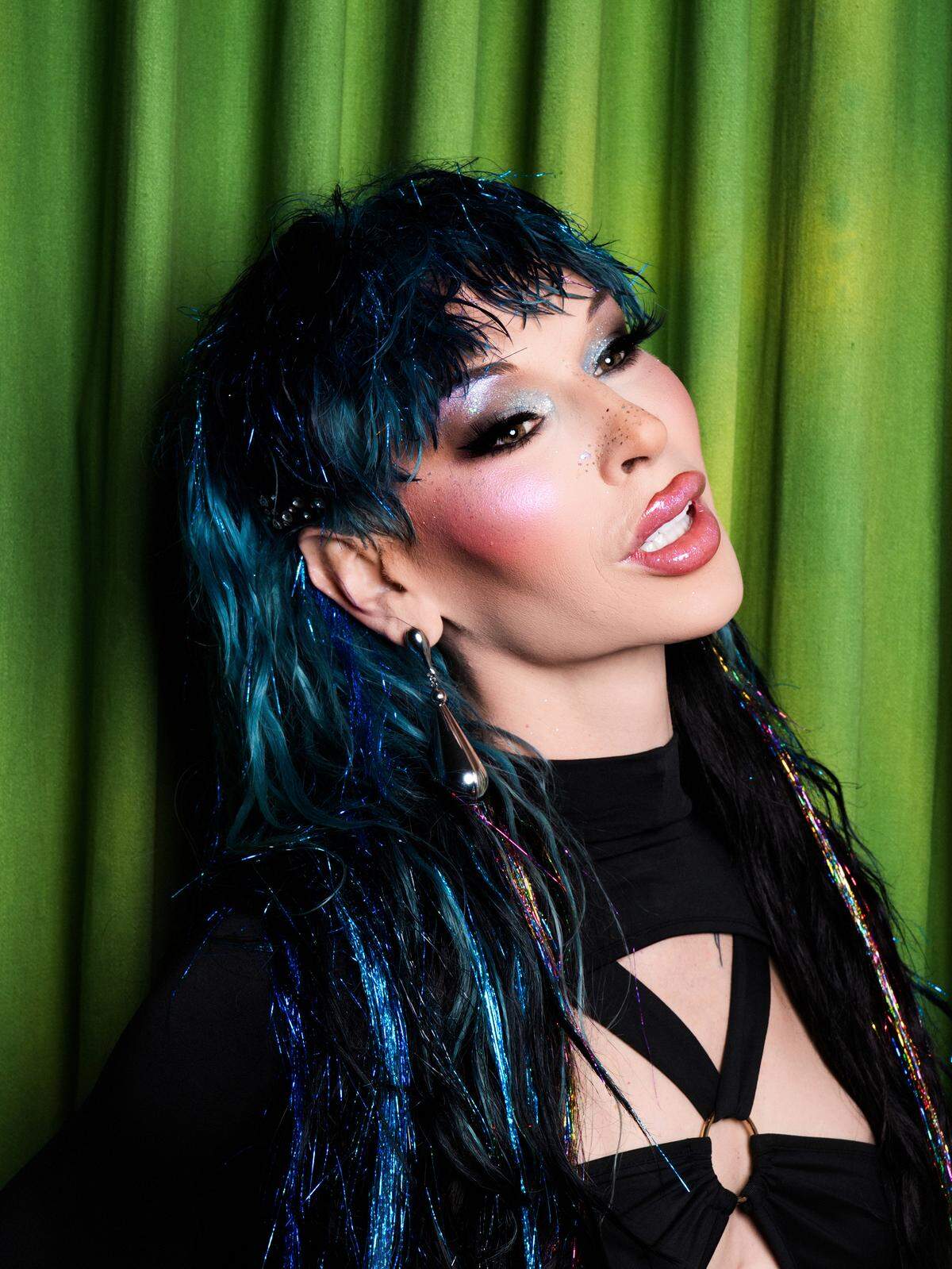 Lexi Love, a finalist on “RuPaul’s Drag Race” Season 17, poses in sparkly teal hair.