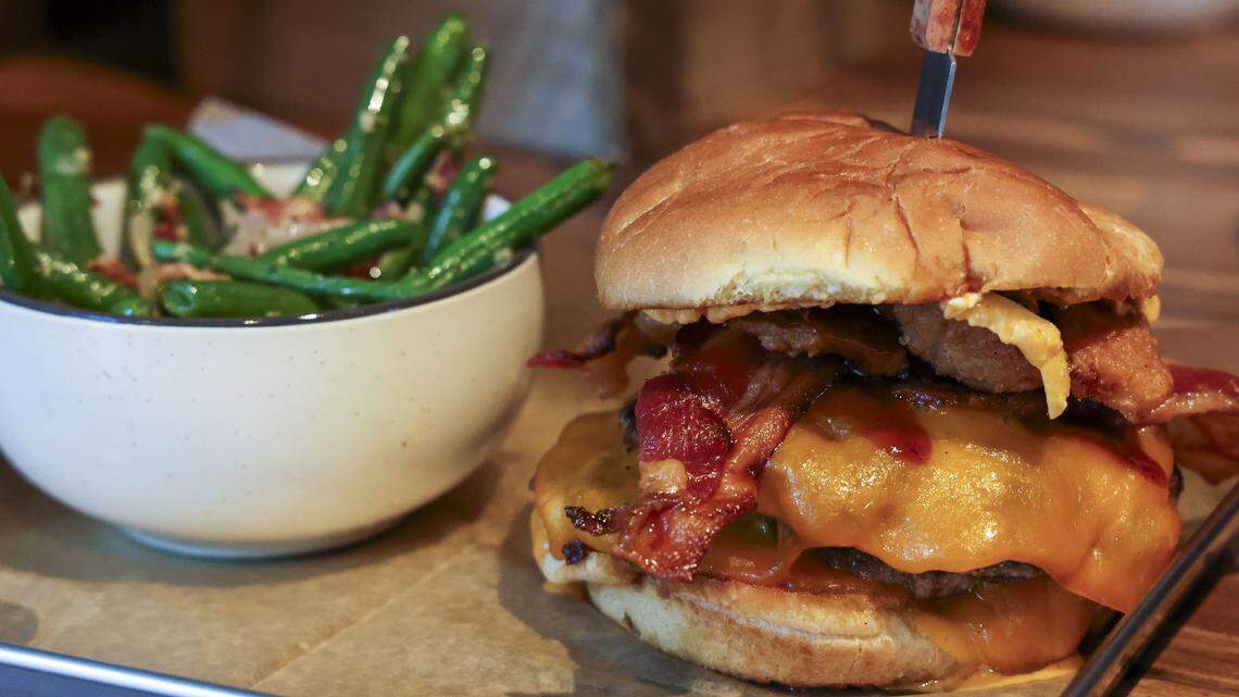 The Southern burger ($18.75) shown with green beans, from Southern Cookhouse & Bar is made with three beef patties from Critchfield Meats Family Market, photographed Sunday, Sept.  7, in Lexington, Ky. and topped with BBQ sauce, applewood bacon, fried onions, cheese and cole slaw.