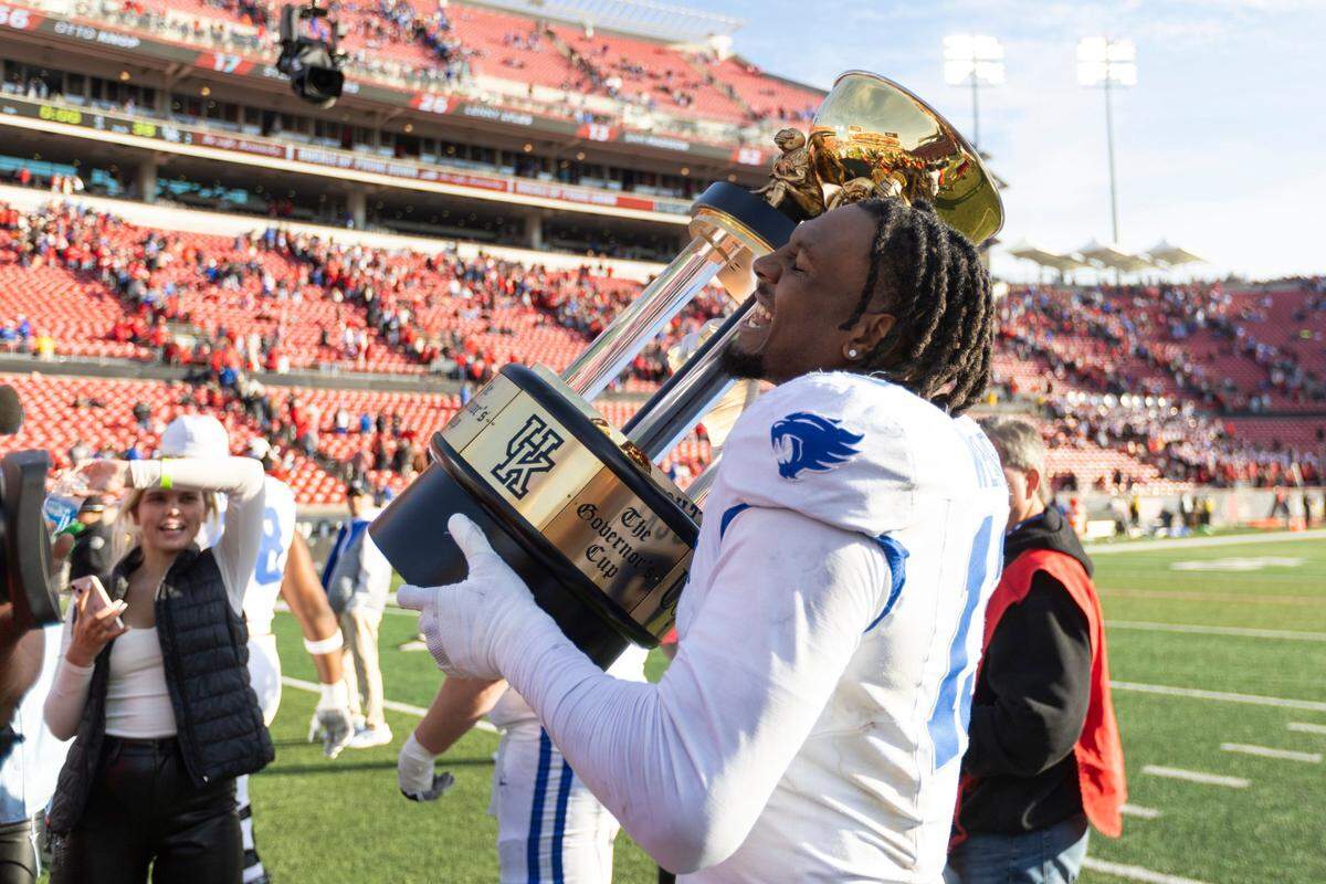Kentucky rush end/outside linebacker J.J. Weaver (13) celebrated with the Governor’s Cup trophy after his strong performance helped the Wildcats beat the No. 9 Cardinals 38-31 last season at L&N Federal Credit Union Stadium.