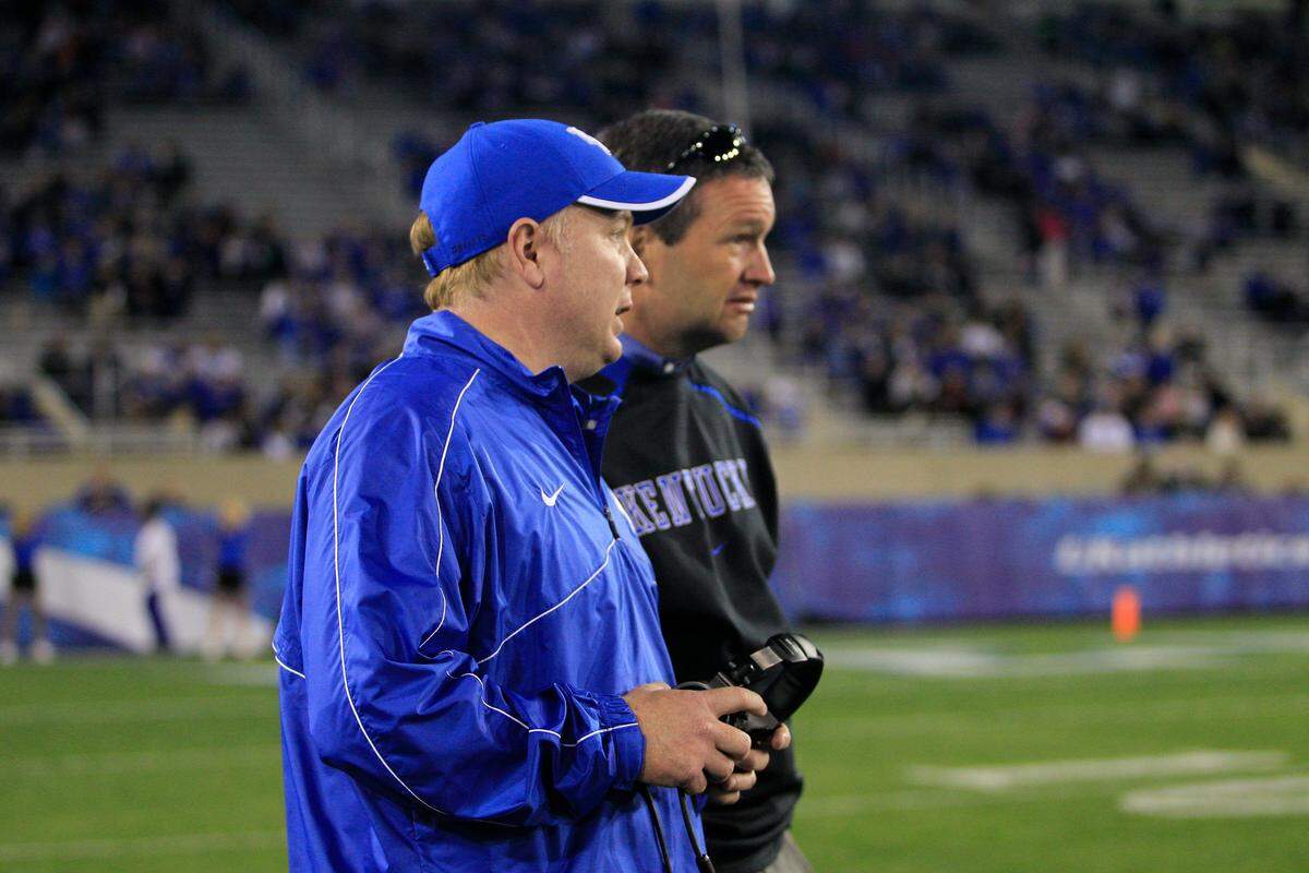 Mark Stoops, forefront, has validated the faith Kentucky Athletics Director Mitch Barnhart, right, showed in him via a generous coaching contract.