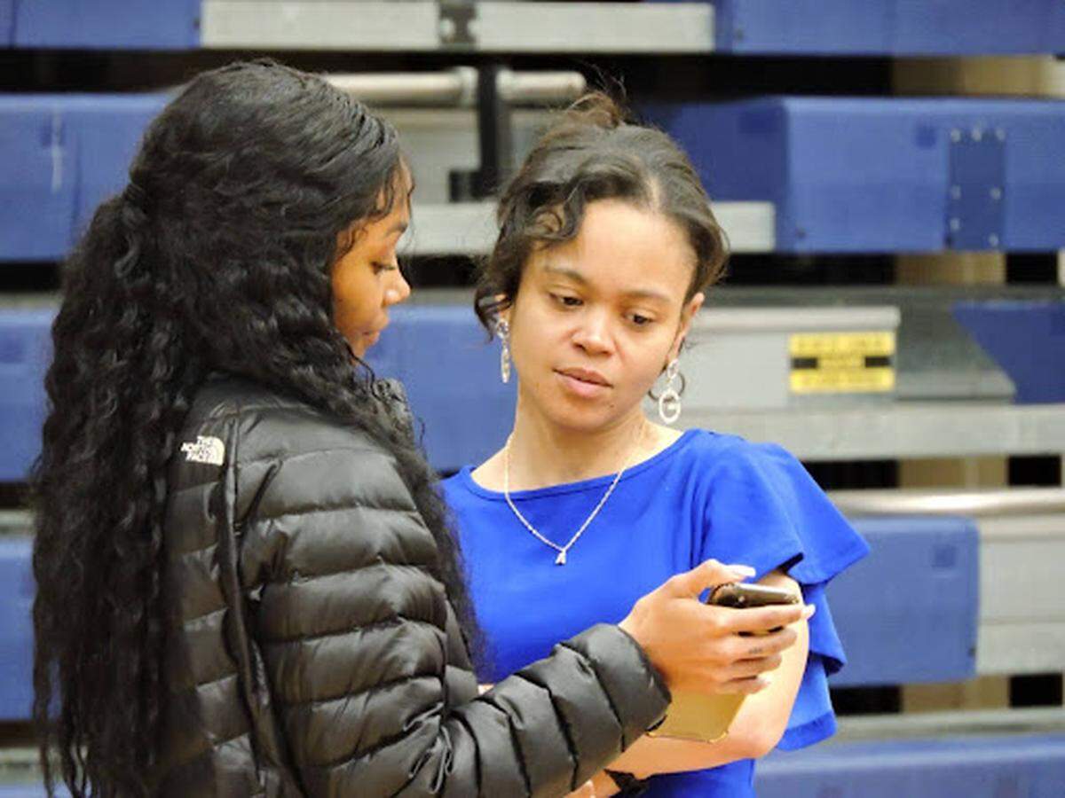 Henry Clay girls basketball coach Ashley Garrard, right, looks at a cell phone screen with her daughter, Asja-Li Garrard, before a game on Feb. 3, 2024.