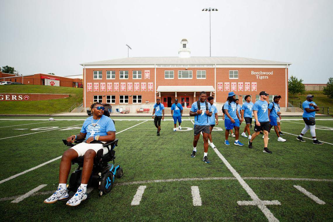 Chris Oats, left, leads out a group of Kentucky football players to start the Chris Oats Football Camp on Saturday at Beechwood High School. “He’s smiling. He’s happy,” Kentucky linebacker J.J. Weaver said. “It’s an honor to be one of his brothers that could be here with him at this camp