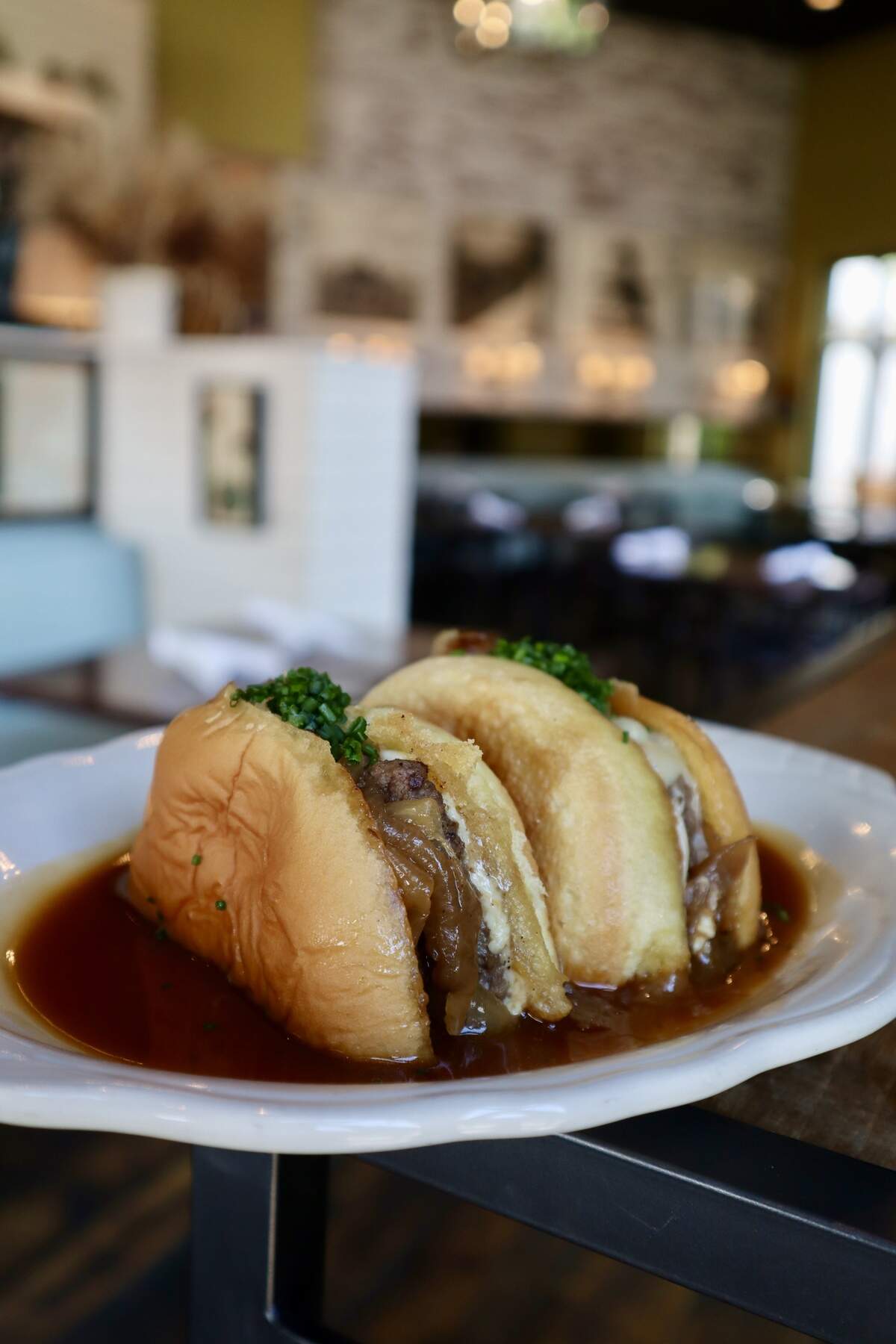 Whiskey Burger from Honeywood, featuring Gruyere cheese, housemade rosemary aioli, and caramelized onions on a garlic toasted butter roll with bourbon gravy.
