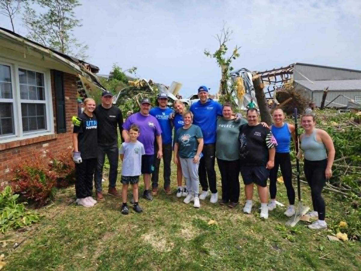 Coach Mark Pope stands alongside former UK basketball player Reed Sheppard while cleaning up storm debris in London, KY.