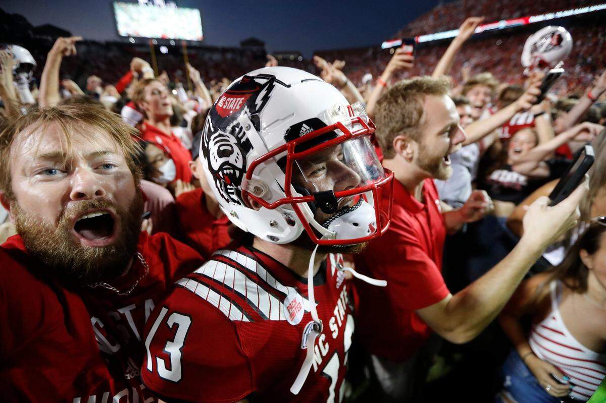 Devin Leary (13) celebrates with fans after N.C. State’s 27-21 overtime victory against Clemson at Carter-Finley Stadium in Raleigh, N.C., on Sept. 25, 2021.