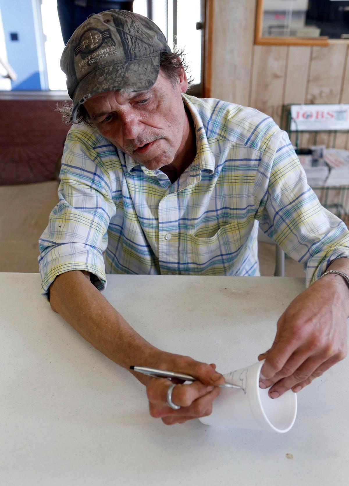 Homeless artist Jeff Maki sketched on a coffee cup in the New Life Day Center.
