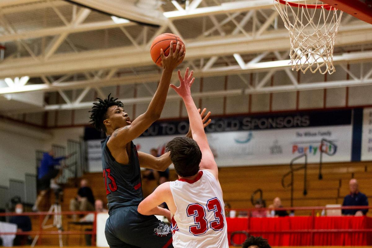 Paul Laurence Dunbar’s Tim Hall (23) went in for a basket against Lafayette’s Abe Nelson (33) during their 43rd District semifinal game at Lafayette on Tuesday night.