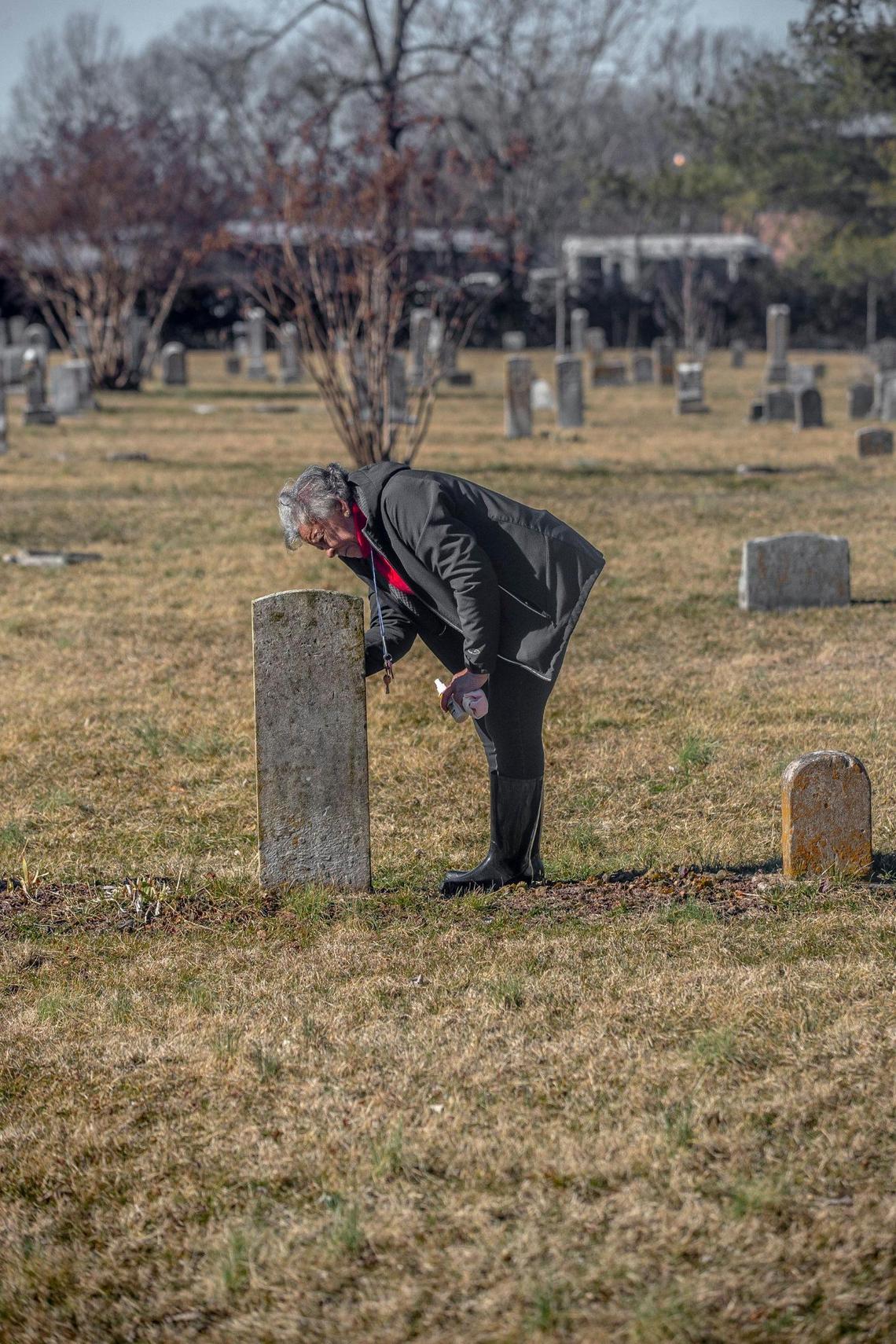 Yvonne Giles scrubs a headstones at African Cemetery No. 2 in Lexington, Ky., on Sunday, Feb. 20, 2022. Giles uses old military records to apply for headstones for veterans whose headstones have gone missing over the years.