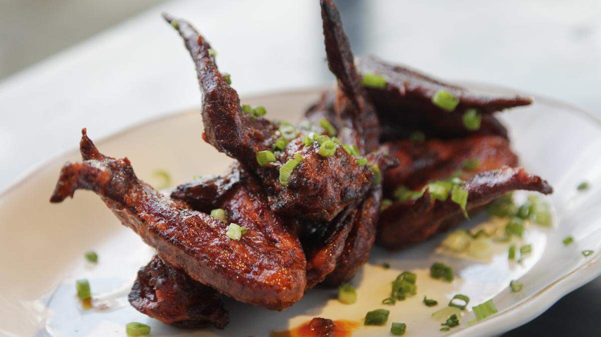 Chicken wings tossed in Sriracha lime sauce are among the choices of smoked-meat dishes at County Club.