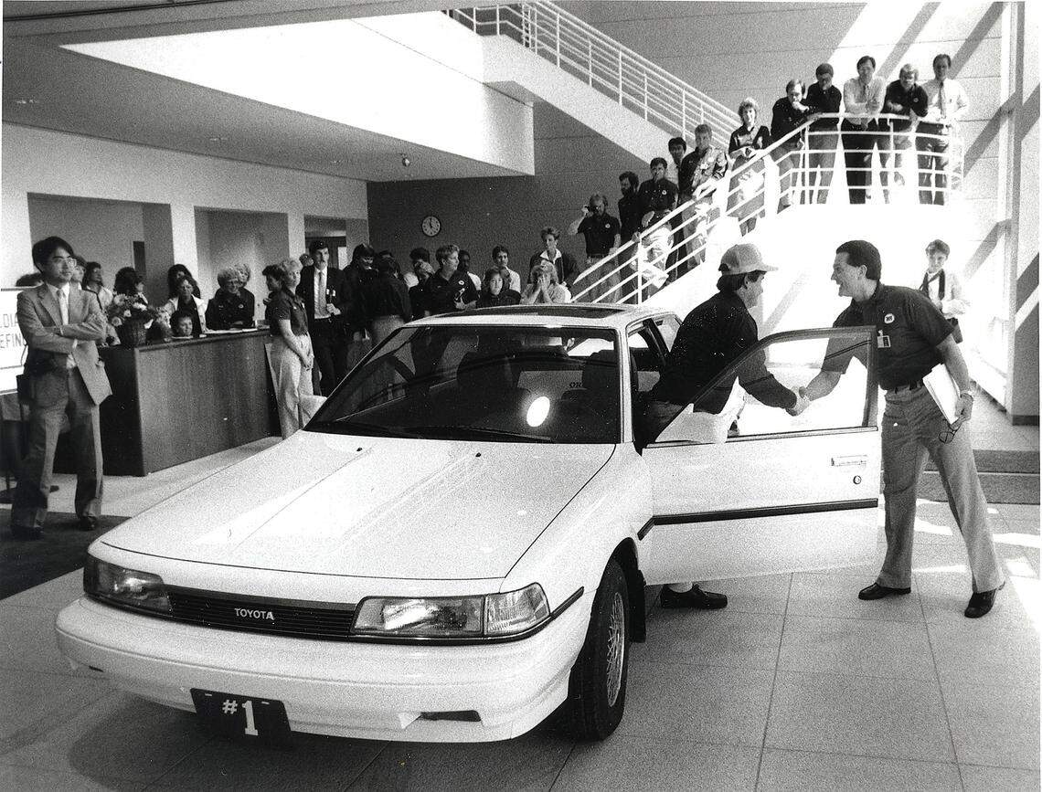 The first Toyota Camry produced at the Georgetown, Kentucky Plant. Mike Dodge (right), the plant’s general manager, shakes hands with Lee Pokriva of the plant’s quality control unit after Pokriva drove the car into the lobby of the administration building. The car was put on permanent display at the plant on May 26, 1988. David Perry | Staff