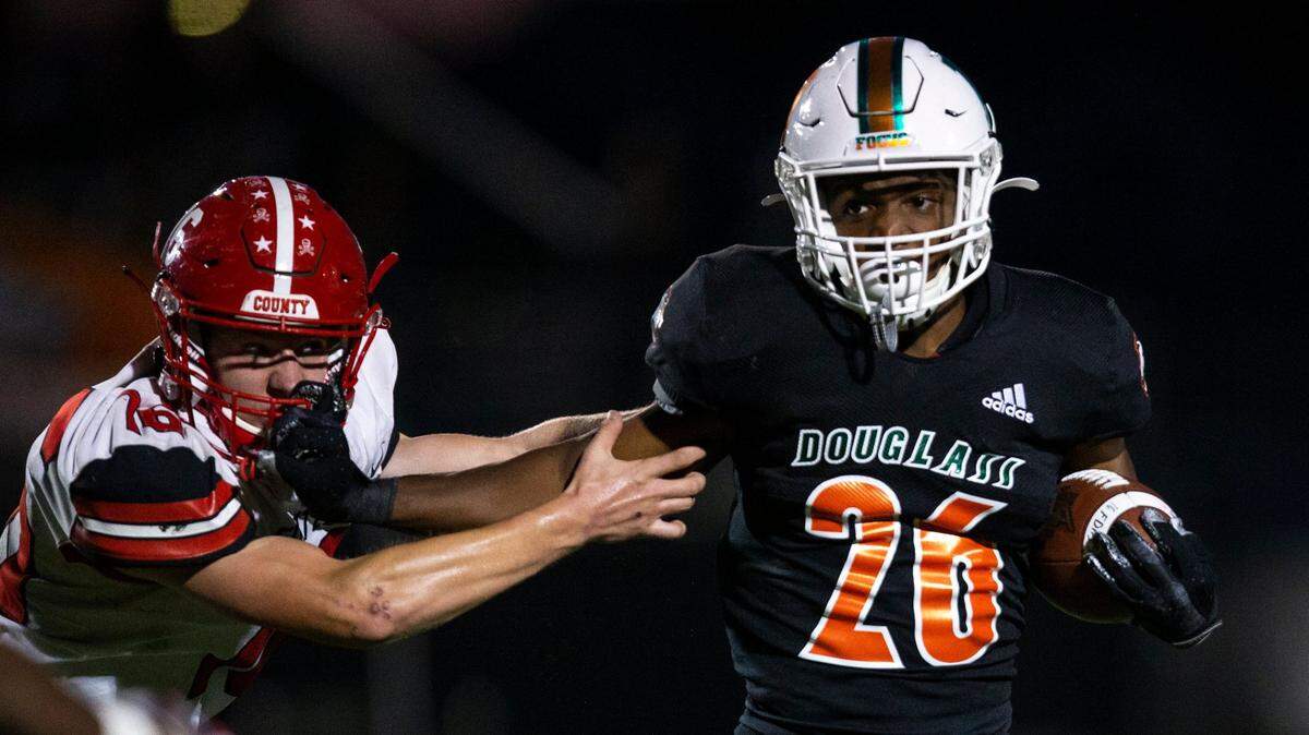 Davaun Hart of Frederick Douglass tries to break away from Scott County tackler Ryan Harris during last season’s meeting in Lexington.