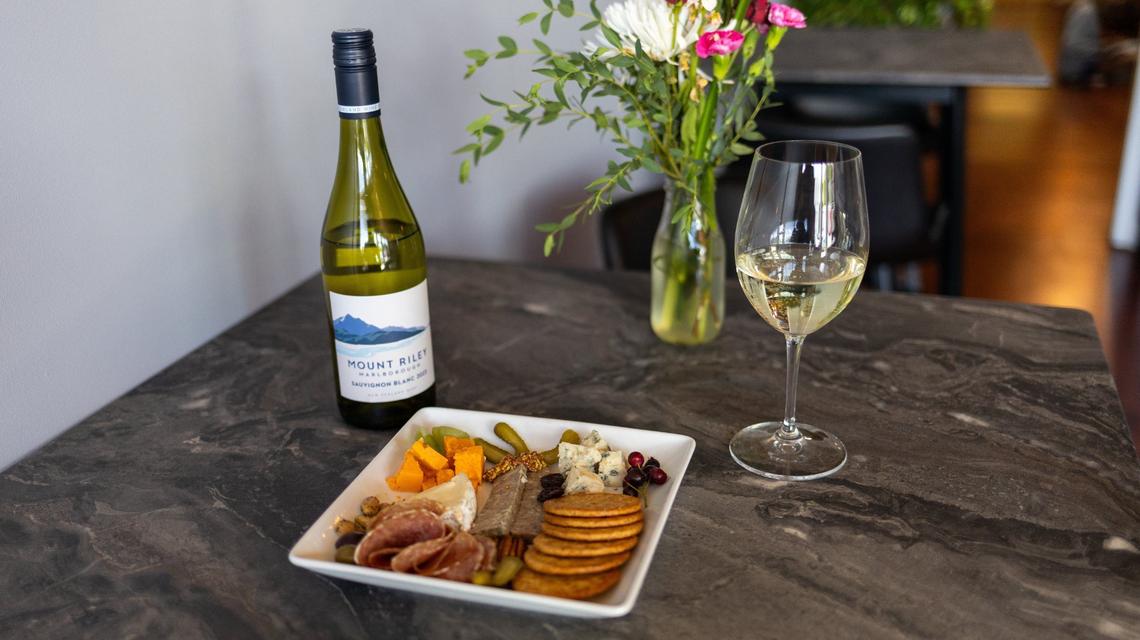 A cup of Mount Riley wine and a charcuterie board of meats, cheeses, veggies and crackers within Cibon grocery and bar on Rosemont Garden. May 28, 2024.