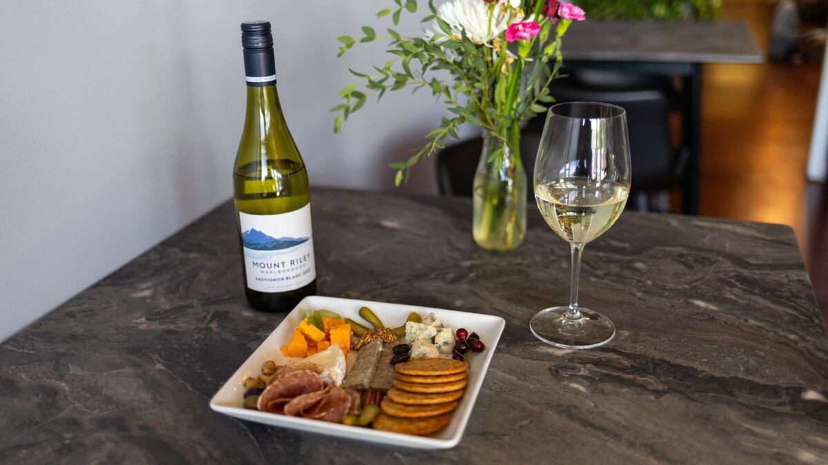 A cup of Mount Riley wine and a charcuterie board of meats, cheeses, veggies and crackers within Cibon grocery and bar on Rosemont Garden. May 28, 2024.