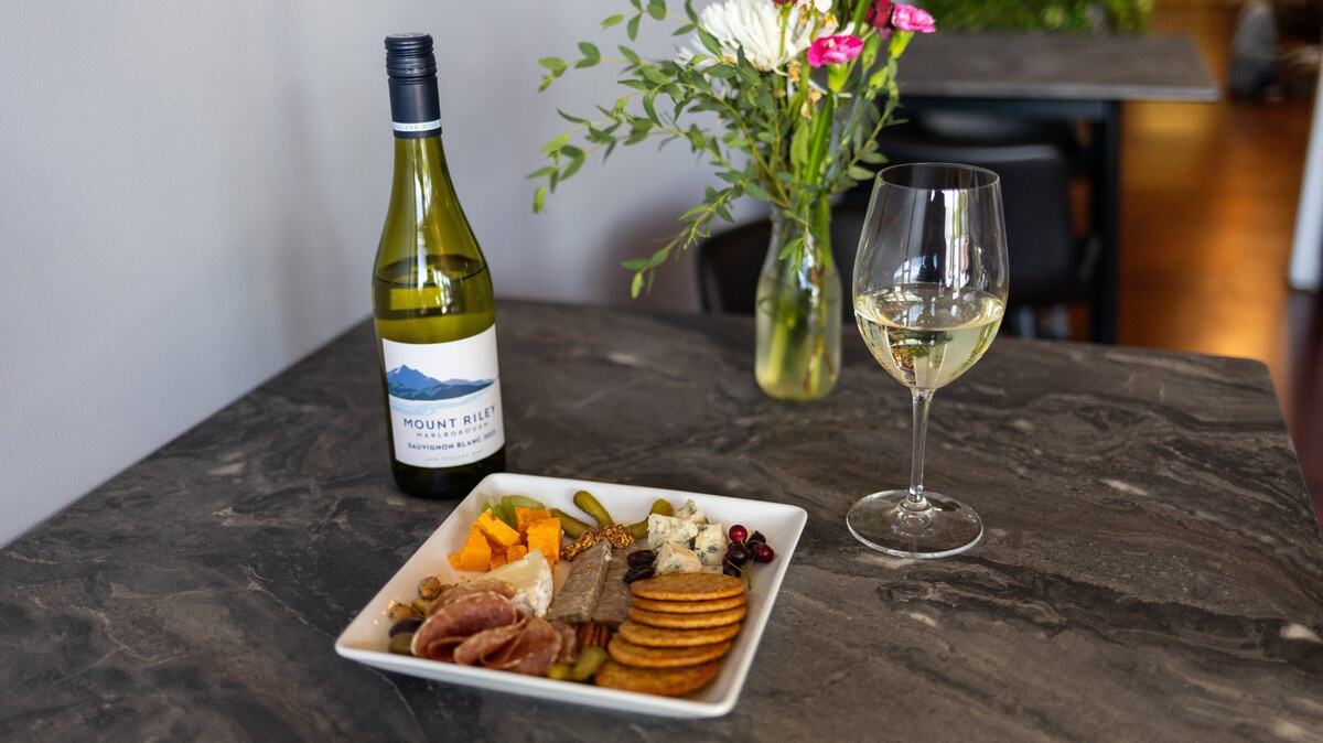 A cup of Mount Riley wine and a charcuterie board of meats, cheeses, veggies and crackers within Cibon grocery and bar on Rosemont Garden. May 28, 2024.