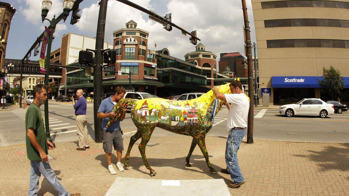 Mark Finfrock, left, watched as John Sprague and Declan Harding, right, placed Henry, A Tribute to Henry Faulkner, by Lexington artist Mary Wathen﻿ at the corner of Broadway and Main streets in downtown Lexington Wednesday as part of Horse Mania 2010.