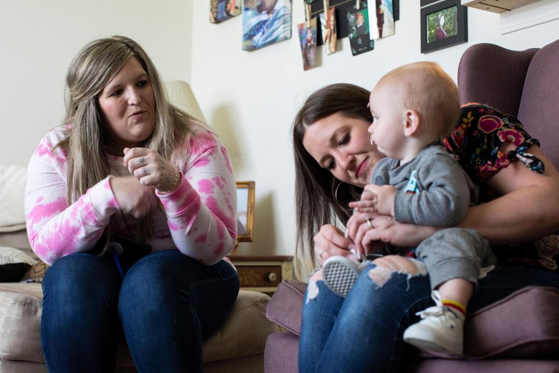 Megan Simpson plays with her youngest son Jaxson while her twin sister Morgan fixes his shoes in Barbourville, Ky., Friday, May 7, 2021. Morgan has been caring for Megan’s three sons while she has been dealing with addiction, recovery and healing from open heart surgery.