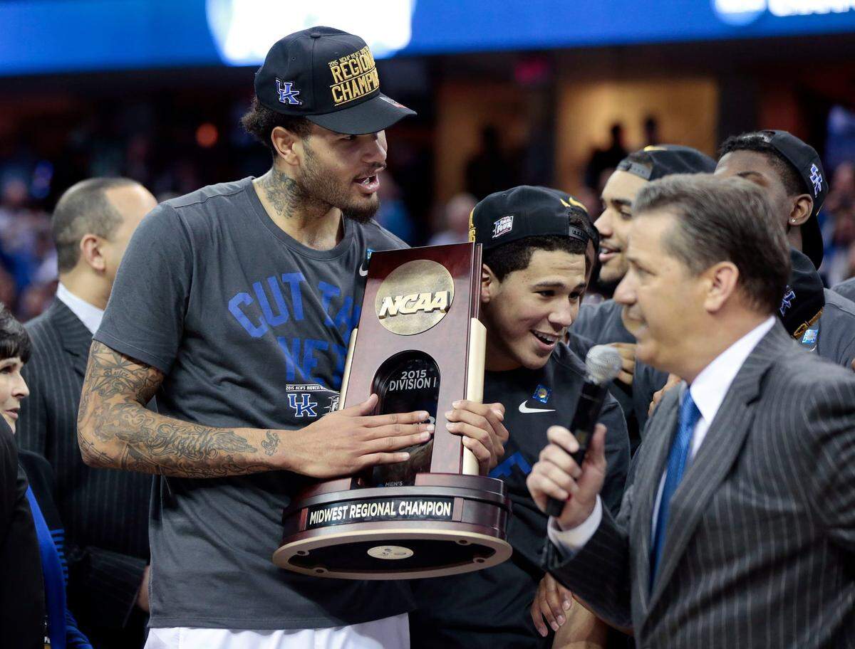Kentucky’s Willie Cauley-Stein and Devin Booker celebrate with the trophy as coach John Calipari speaks following UK’s win over Notre Dame that sent the Wildcats to the 2015 Final Four.