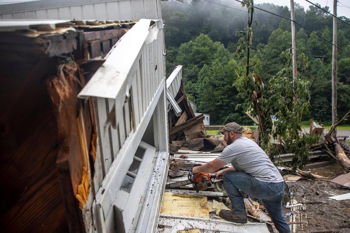 Sammy Gibson uses a chainsaw to cut apart a house that came to rest on a bridge over Sandlick Creek near the Whitesburg Recycling Center in Letcher County, Ky., on Friday, July 29, 2022.