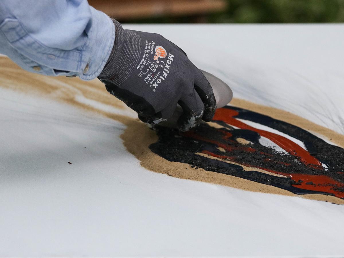In his back yard, Ishmael pours coal onto a canvas, demonstrating his artistic process.