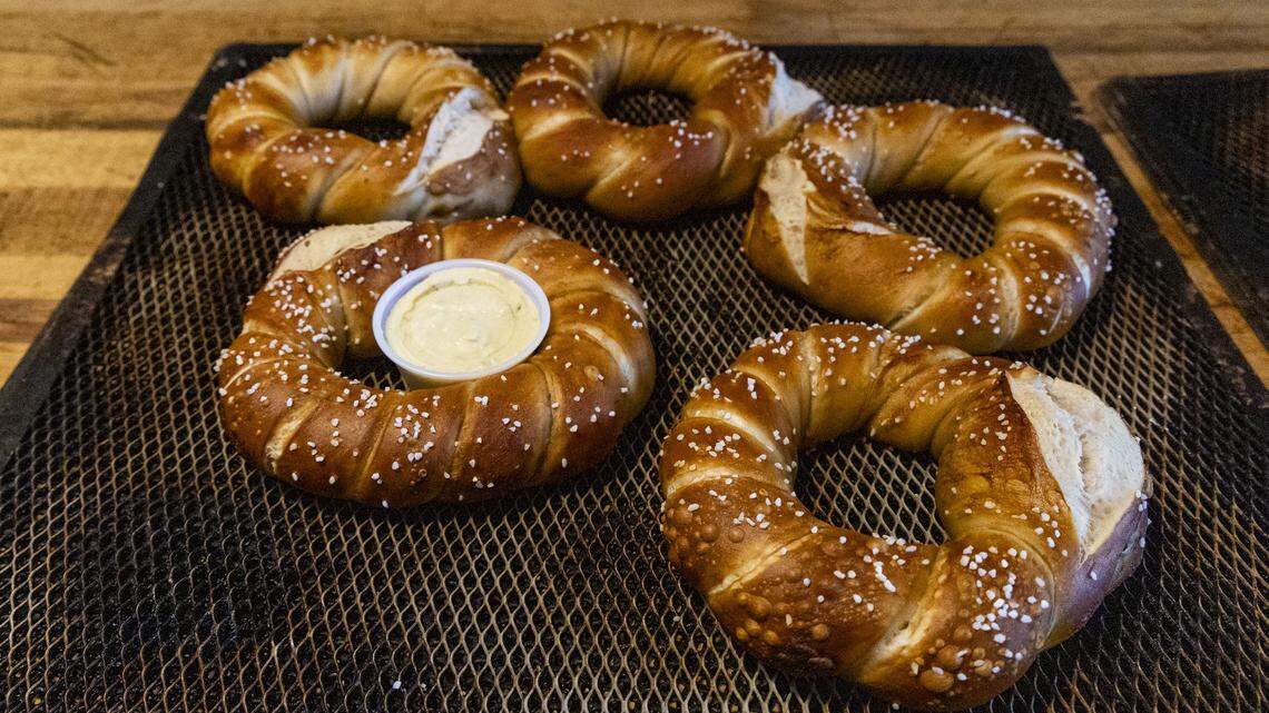 Four, 7 oz. Papa Pretzel’s fresh from the oven, Tuesday, March 24, 2026, at The Wandering Bock Pretzel Pub & Brat Haus in Lexington, Ky. The sourdough pretzels are baked in a four deck, small pizza oven for just under 15 minutes. The pretzels are Swabian style, not the more common Bavarian. They have a higher fat content (butter) and a thick, soft belly that is often with a scored cut.