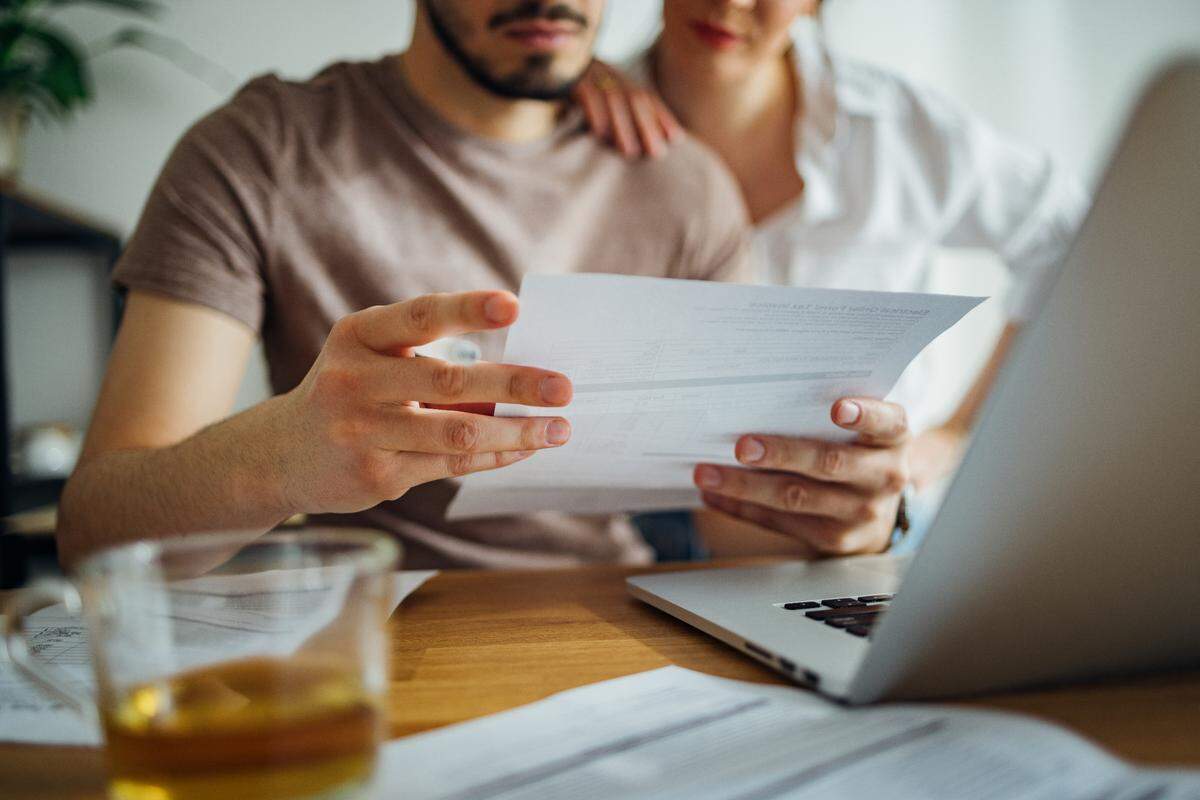 The stock image shows a close up of a couple doing their finances together at home.