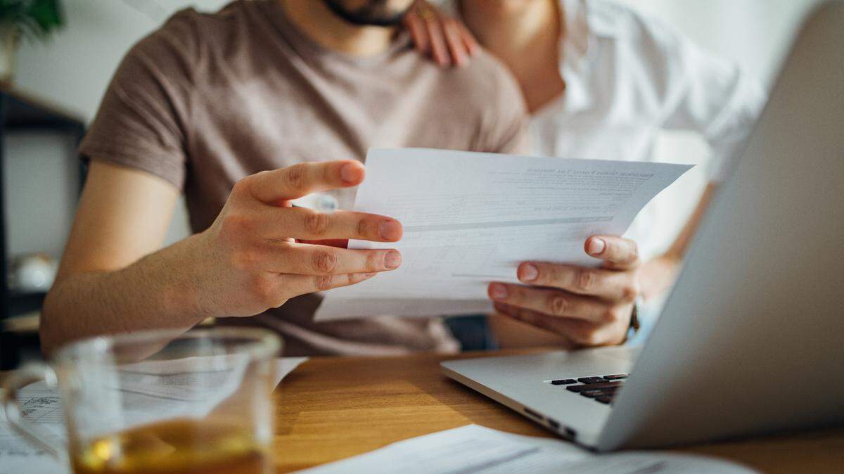 The stock image shows a close up of a couple doing their finances together at home.