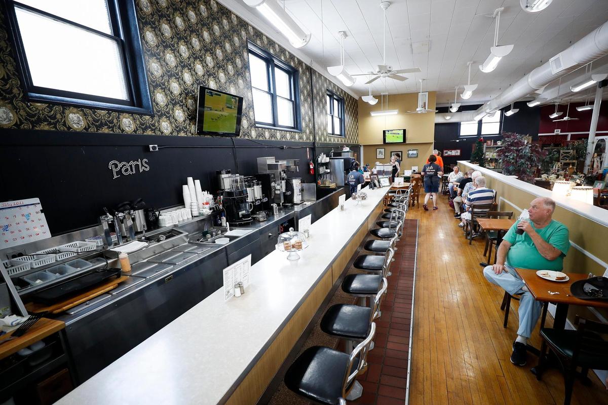 John Smits, of Paris, watches television while eating a chicken salad sandwich at Lil’s Coffee House July 2, 2021. The restaurant has been open for 10 years and everything is homemade.