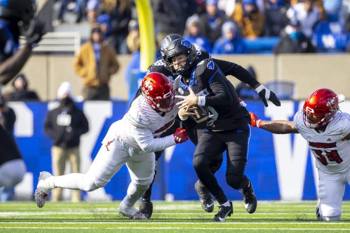 Kentucky quarterback Cutter Boley (8) is chased by Louisville defensive lineman Jordan Guerad (94) and linebacker TJ Quinn (34) during Saturday’s game at Kroger Field.